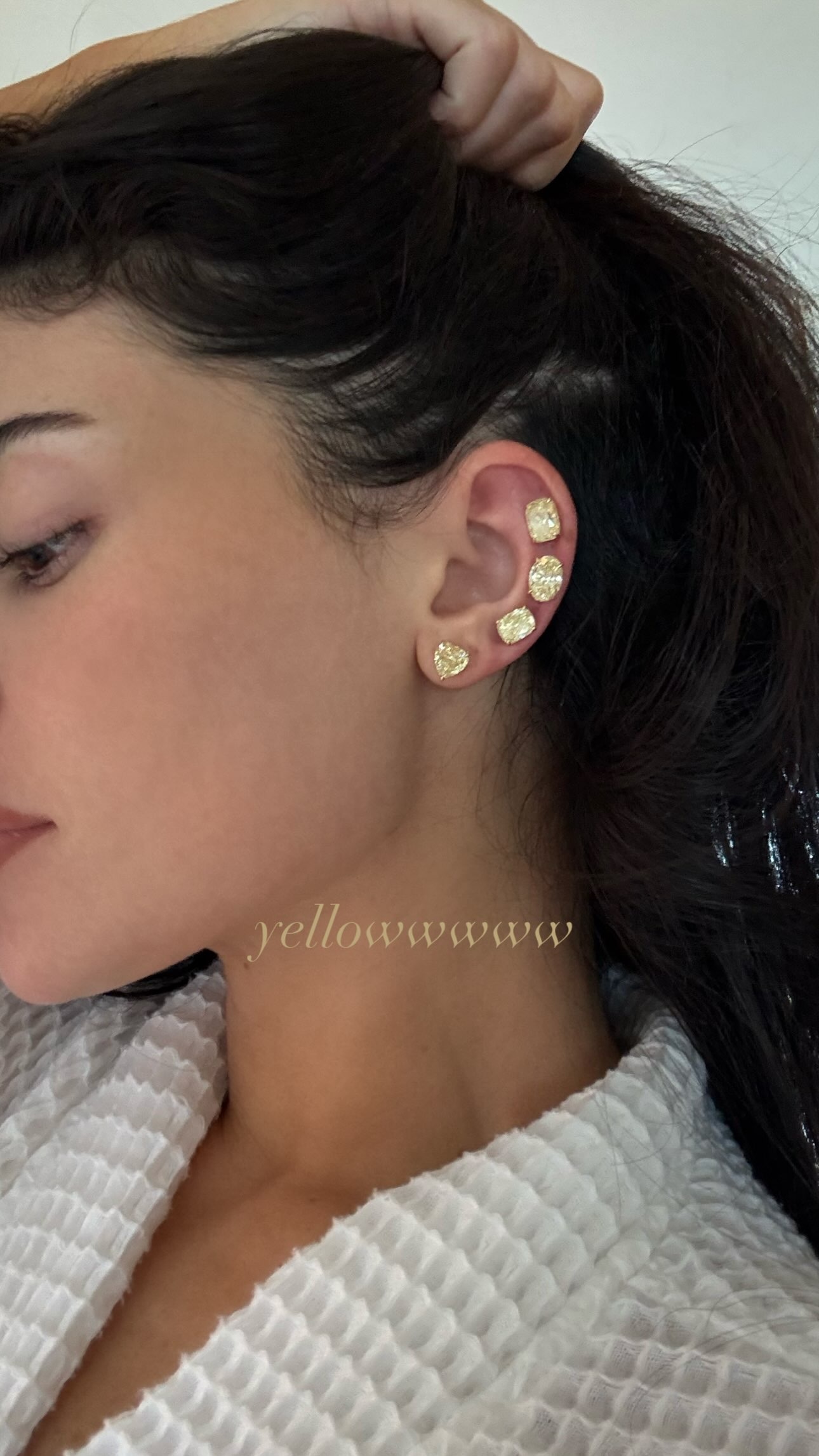 Close-up of Kylie Jenner's ear showing four yellow diamond stud earrings in different shapes climbing the lobe