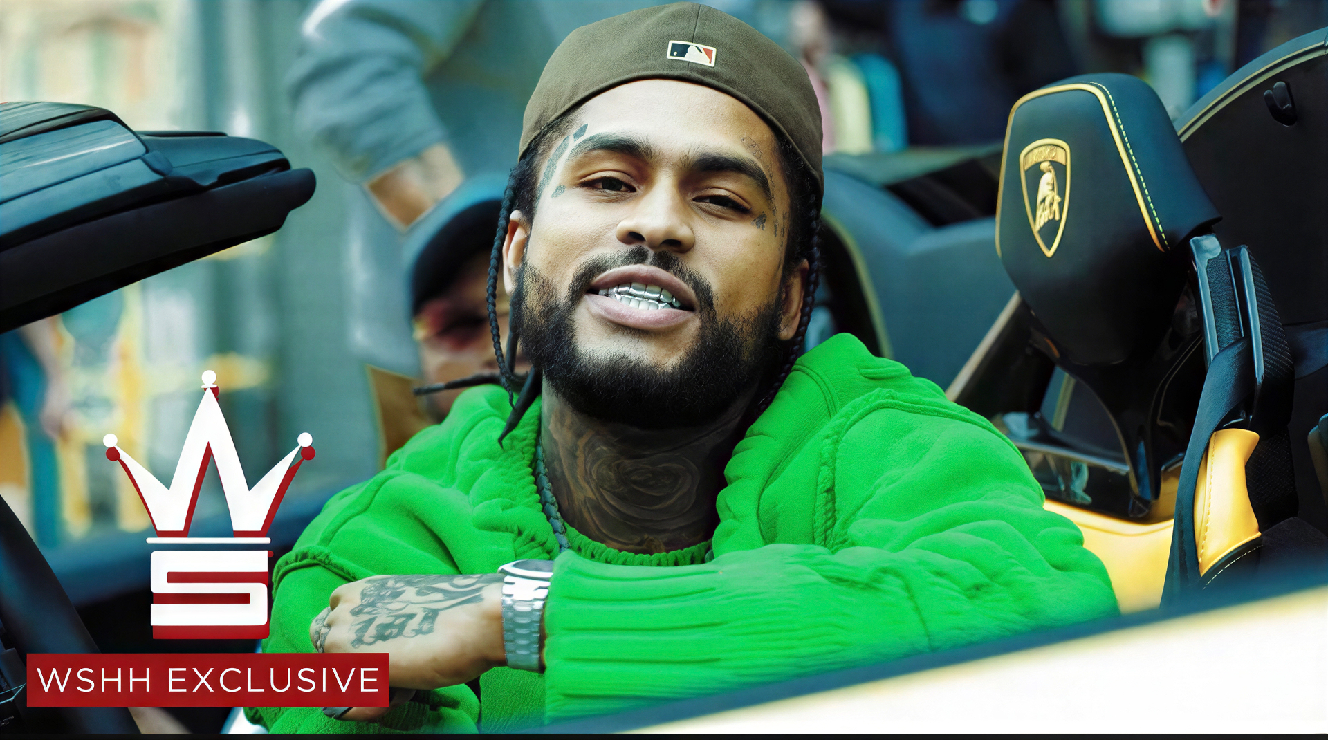 Dave East in a green sweater wearing custom Gumbo Grillz, seated in a Lamborghini