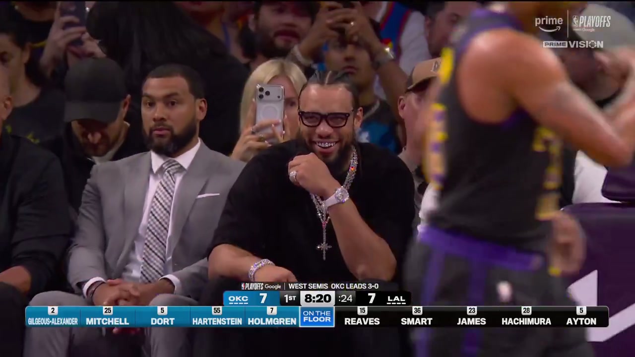 Broadcast frame of Dillon Brooks smiling with his diamond grill, layered chains, watch and ring visible