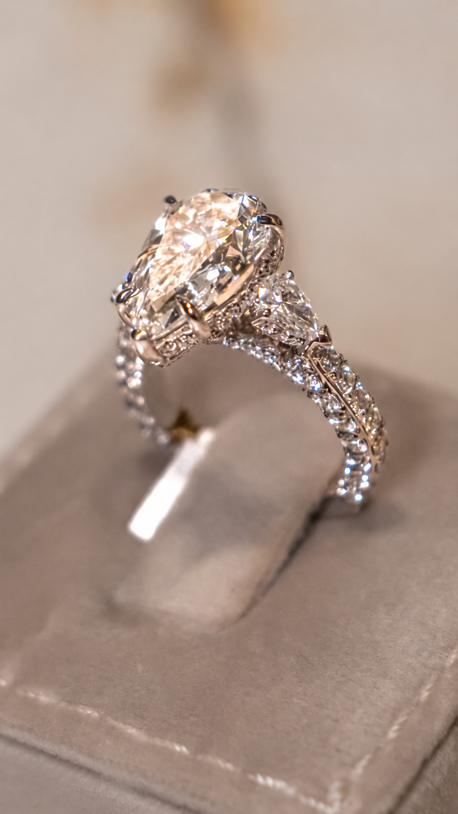 Angled view of an oval center stone ring with side accents and pavé set band