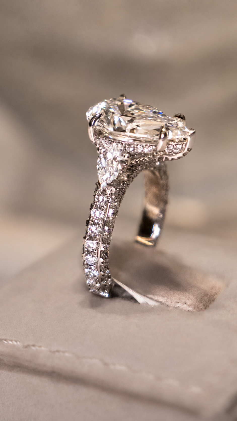 Profile view of an oval center stone ring with detailed shoulders and pavé set band