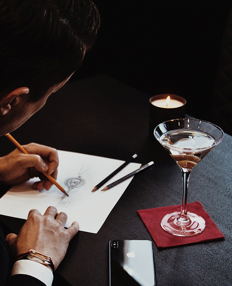 A hand sketches a ring during the bespoke design process