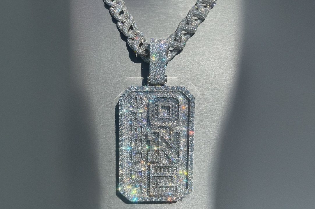 The diamond Breed of One pendant and Cuban link chain photographed against a gray backdrop